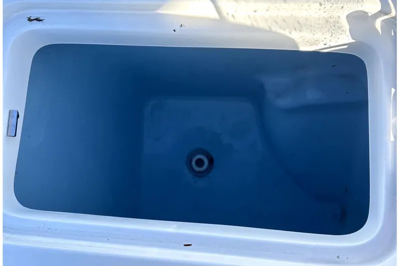 Slide: The Image of 2023 Pioneer 222 Islander boat livewell, empty and clean, with drain visible. - 22
