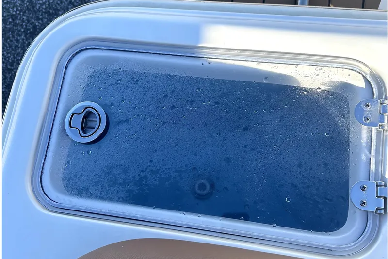 Slide: The Image of 2023 Pioneer 222 Islander boat compartment with a wet, transparent lid and secure latch. - 23