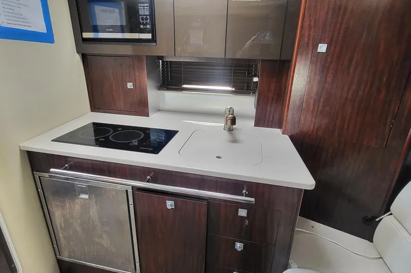 Slide: The Image of 2016 Monterey 335 Sport Yacht kitchen with stove, sink, and microwave. - 18