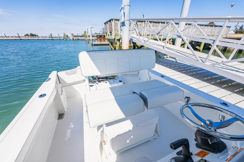 Slide: The Image of 2023 Parker 2400 boat interior at dock, featuring white seating and steering wheel. - 11