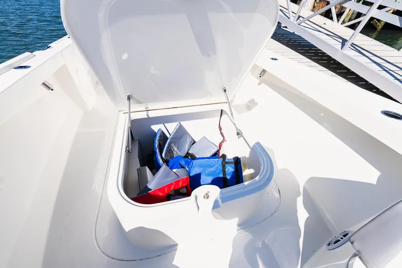 Slide: The Image of Open storage compartment on 2023 Parker 2400 boat, containing colorful bags. - 15