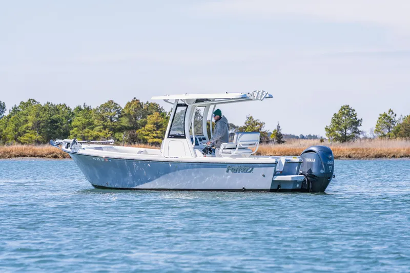 Slide: The Image of 2023 Parker 2400 boat cruising on a calm lake with trees in the background. - 2