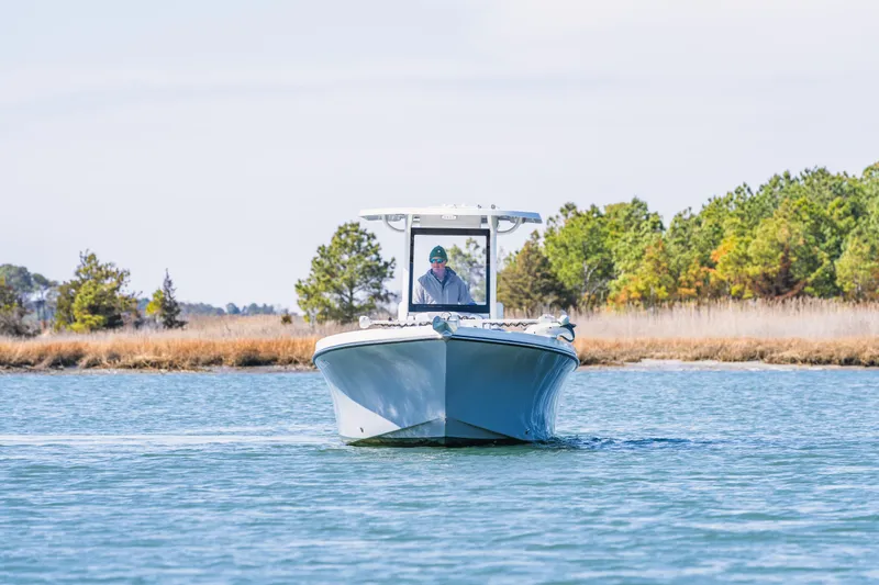 Slide: The Image of 2023 Parker 2400 boat cruising on a serene lake with trees in the background. - 6