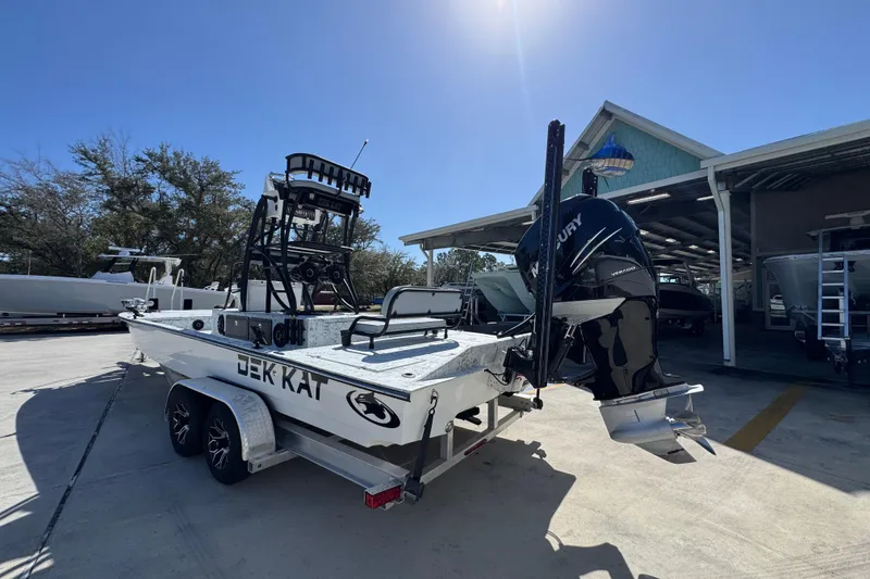 Slide: The Image of 2023 Dek Kat 27 Trilogy boat on trailer with Mercury engine, parked outdoors. - 14