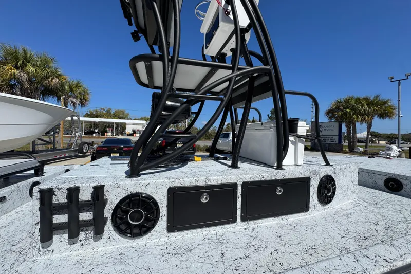 Slide: The Image of 2023 Dek Kat 27 Trilogy boat deck with storage, speakers, and rod holders under clear blue sky. - 27