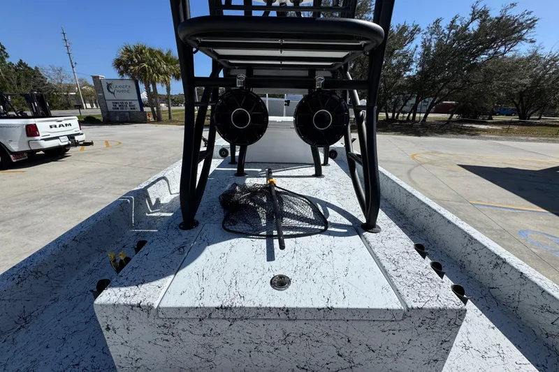 Slide: The Image of 2023 Dek Kat 27 Trilogy boat with fishing net on deck, parked outdoors. - 29