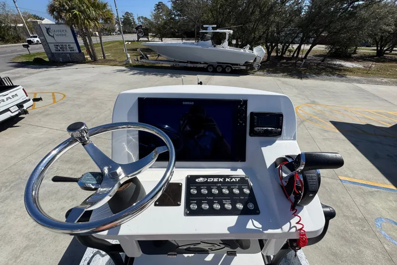Slide: The Image of 2023 Dek Kat 27 Trilogy boat dashboard with steering wheel and control panel. - 31