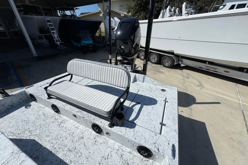 Slide: The Image of 2023 Dek Kat 27 Trilogy boat with bench seating and outboard motor in a marina. - 35