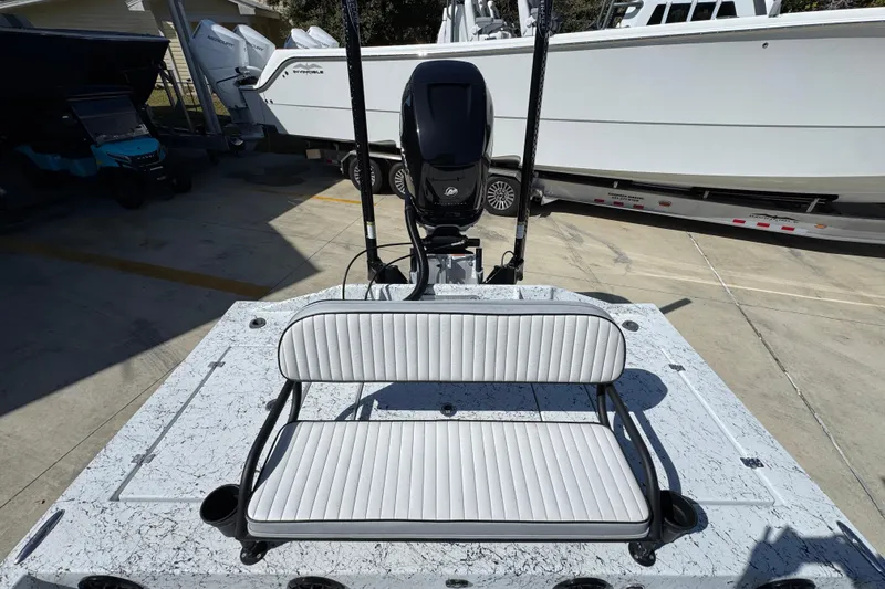 Slide: The Image of 2023 Dek Kat 27 Trilogy boat with white seating and motor, parked in a marina. - 36