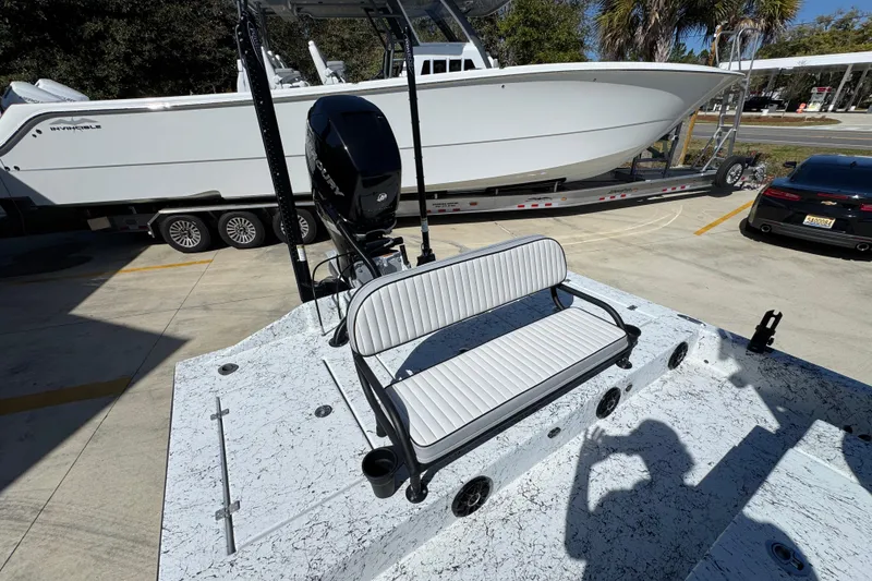 Slide: The Image of 2023 Dek Kat 27 Trilogy boat with seating and motor, parked near a trailer and car. - 37
