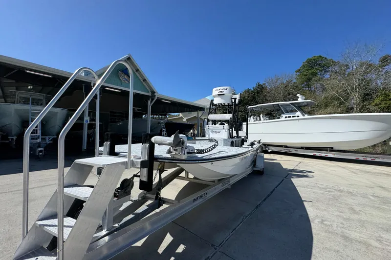 Slide: The Image of 2023 Dek Kat 27 Trilogy boat on trailer at marina under clear blue sky. - 4