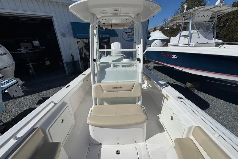 Slide: The Image of 2015 Everglades 243 Center Console boat with beige seating, docked near other boats. - 14