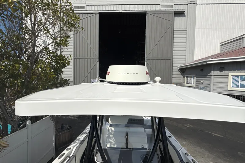 Slide: The Image of 2018 Blackfin 212 CC boat with radar, docked near a large warehouse. - 13