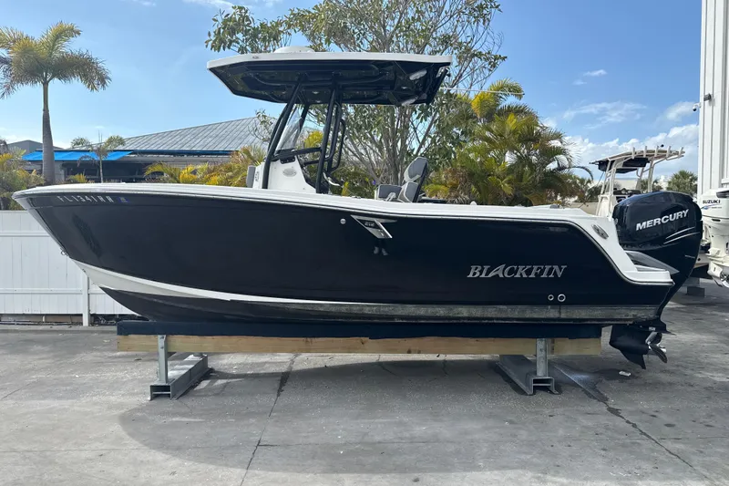 Slide: The Image of 2018 Blackfin 212 CC boat with Mercury engine, displayed outdoors on a stand. - 18