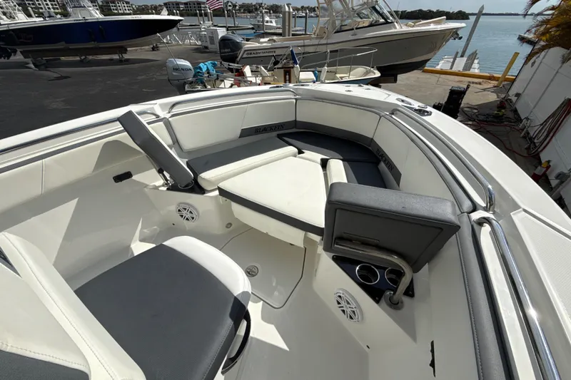 Slide: The Image of 2018 Blackfin 212 CC boat interior with seating and cup holders, docked near water. - 7