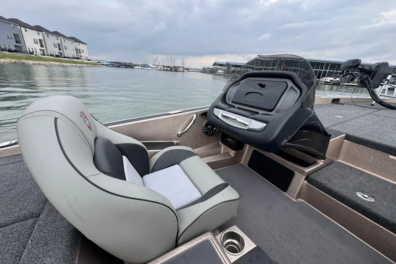 Slide: The Image of 2026 Triton 18 TrX boat interior with steering console, docked by waterfront buildings. - 22
