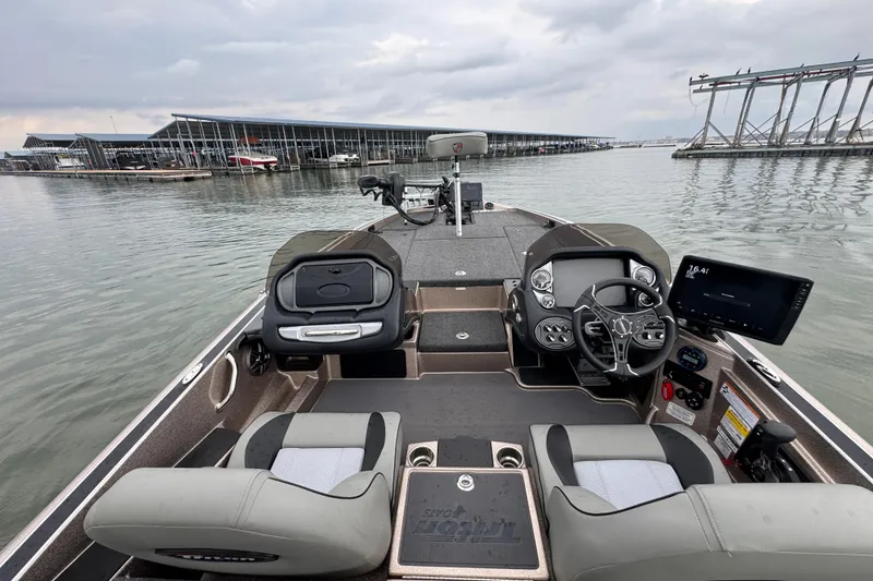 Slide: The Image of 2026 Triton 18 TrX boat interior with modern dashboard and seating, docked at marina. - 24