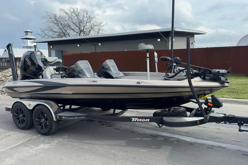 Slide: The Image of 2026 Triton 18 TrX boat on trailer, parked outdoors near a building. - 7