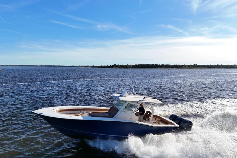 Slide: The Image of 2017 Scout 350 LXF boat cruising on open water under a clear blue sky. - 31