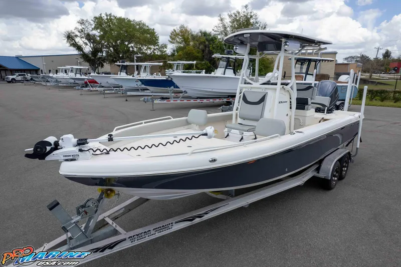 Slide: The Image of 2021 Skeeter SX2550 Family boat on trailer, parked outdoors with other boats in background. - 37