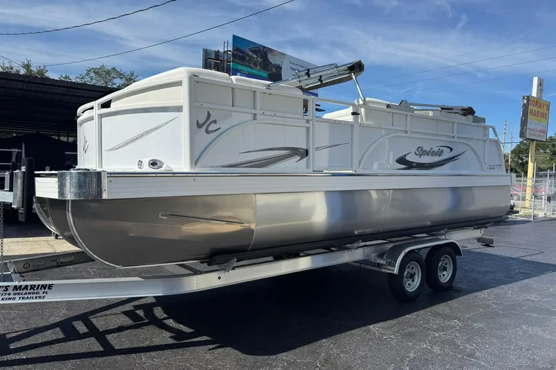 Slide: The Image of 2026 JC Spirit 222 TT Sport pontoon boat on trailer at a marina. - 4