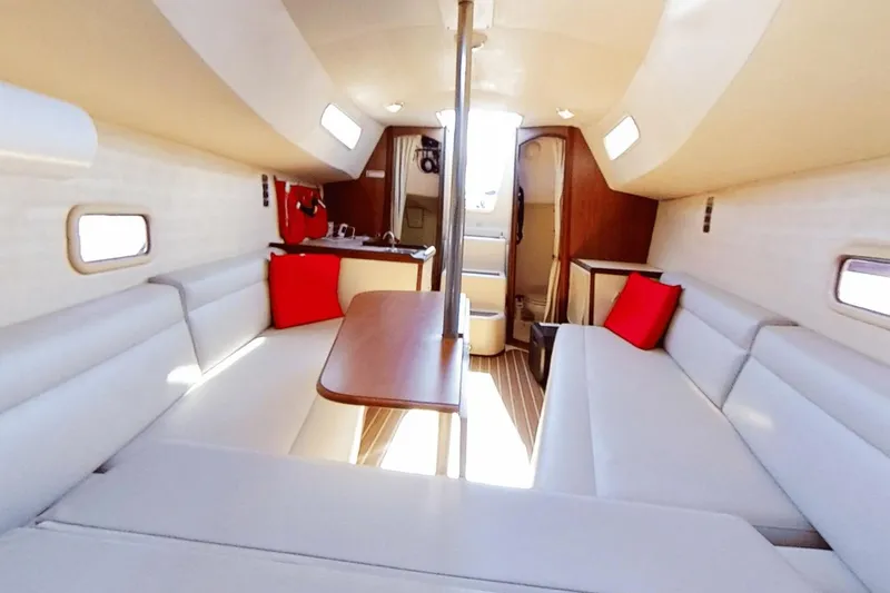 Slide: The Image of Interior of a 2006 Hunter 27 sailboat with white seating and red cushions. - 12