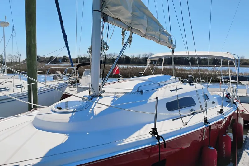 Slide: The Image of 2006 Hunter 27 sailboat docked, featuring a sleek red hull and white deck. - 2