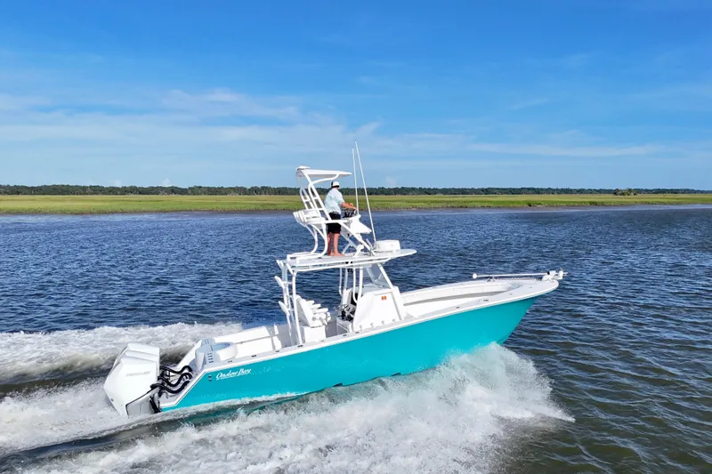 Slide: The Image of 2021 Onslow Bay 33 Tournament boat cruising on a scenic waterway under clear blue skies. - 2