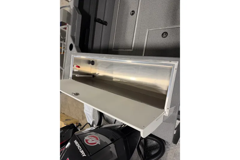 Slide: The Image of 2026 Lund 210 Heavy Gauge boat interior with open storage compartment and Mercury engine. - 11