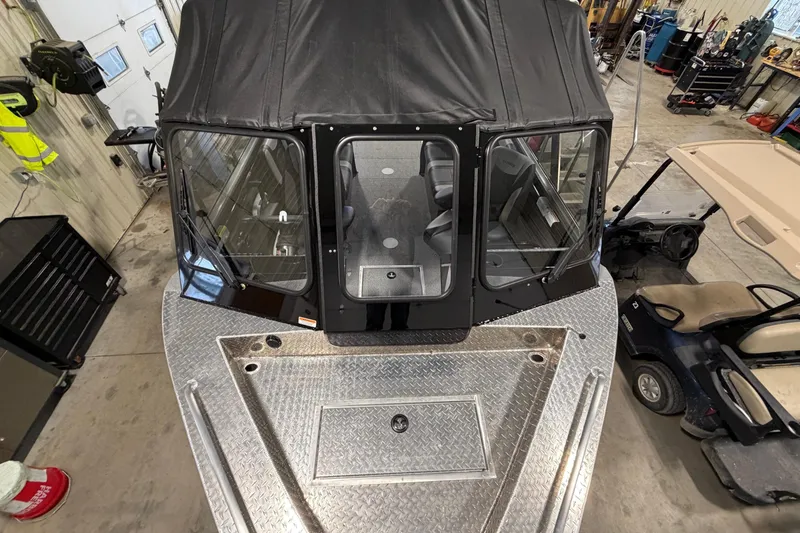 Slide: The Image of 2026 Lund 210 Heavy Gauge boat in a garage, featuring a sturdy metal deck and enclosed cabin. - 15