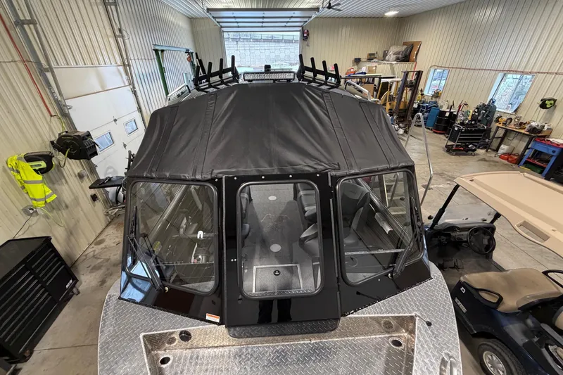 Slide: The Image of 2026 Lund 210 Heavy Gauge boat in a workshop, featuring a covered cabin. - 16