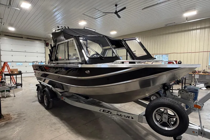 Slide: The Image of 2026 Lund 210 Heavy Gauge boat on trailer in a spacious indoor garage. - 4