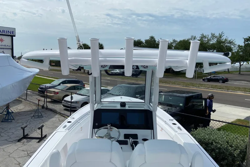 Slide: The Image of 2026 Sportsman Masters 267 Bay Boat with T-top and rod holders, parked near a road. - 21