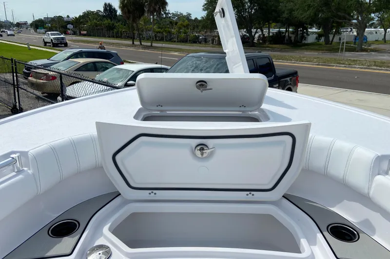 Slide: The Image of 2026 Sportsman Masters 267 Bay Boat with open storage compartments, parked near a road. - 28