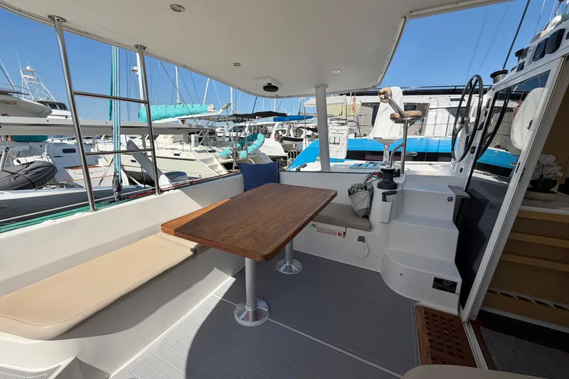 Slide: The Image of 2014 Outremer 45 catamaran cockpit with seating, table, and helm, docked at marina. - 10