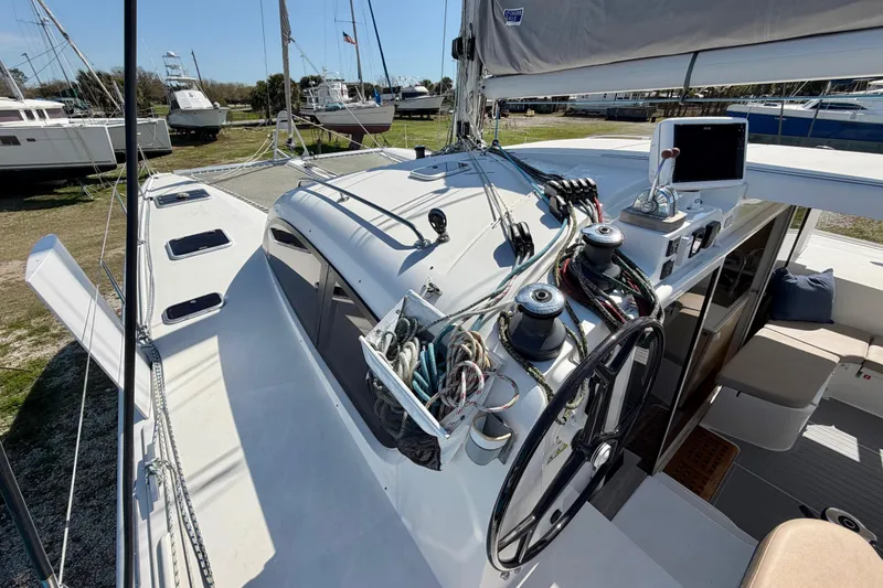Slide: The Image of 2014 Outremer 45 catamaran deck with steering wheel and rigging, docked in a marina. - 16