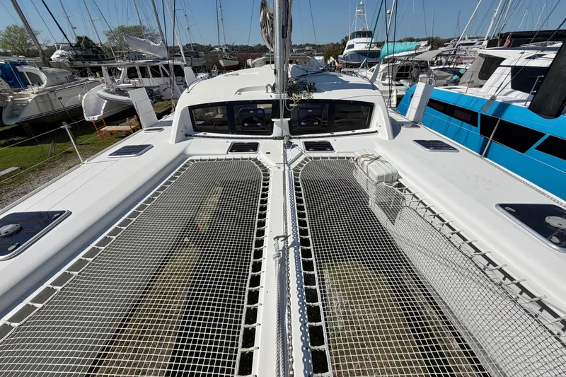 Slide: The Image of 2014 Outremer 45 catamaran deck with netting, docked among other boats. - 19