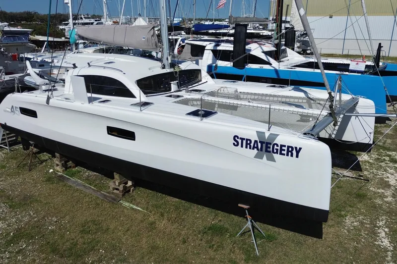 Slide: The Image of 2014 Outremer 45 catamaran "Strategery" on land, surrounded by other boats. - 2