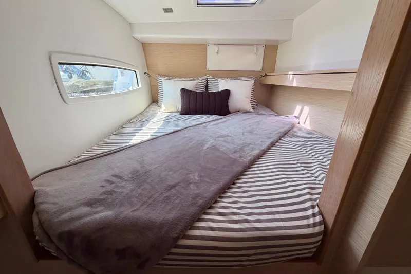 Slide: The Image of Cozy cabin interior of 2014 Outremer 45 yacht with striped bedding and window view. - 45