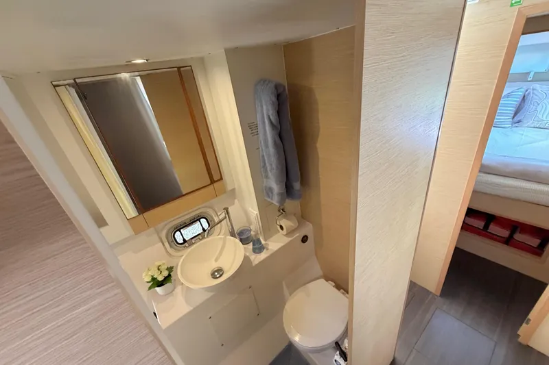 Slide: The Image of 2014 Outremer 45 yacht bathroom with sink, mirror, and adjacent bedroom view. - 57