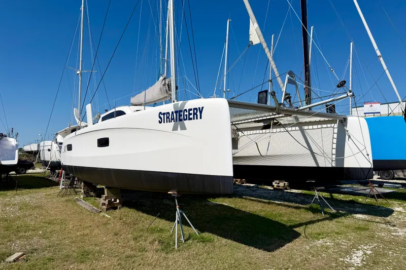 Slide: The Image of 2014 Outremer 45 catamaran "Strategery" on land, white hull, blue sky background. - 92