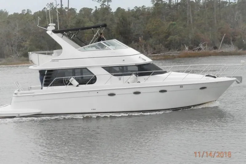 Slide: The Image of 2000 Carver 450 Voyager Pilothouse yacht cruising on a calm river. - 2