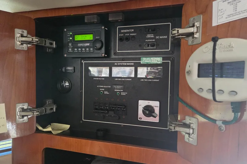 Slide: The Image of Electrical control panel inside 2000 Carver 450 Voyager Pilothouse boat, featuring generator and AC system controls. - 48