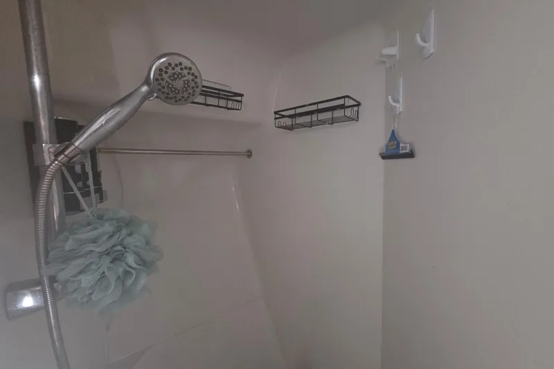 Slide: The Image of Shower area in a 2000 Carver 450 Voyager Pilothouse with handheld showerhead and storage racks. - 75