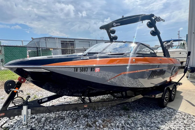 Slide: The Image of A 2023 Malibu Wakesetter 23 LSV on a trailer, featuring orange accents and a tower. - 11