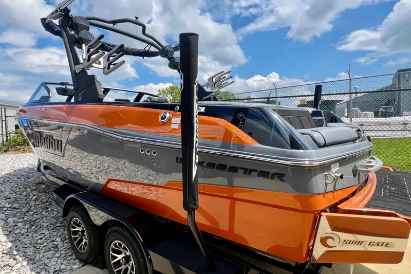 Slide: The Image of 2023 Malibu Wakesetter 23 LSV boat with vibrant orange and gray design on a trailer. - 12