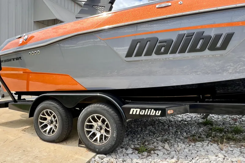 Slide: The Image of 2023 Malibu Wakesetter 23 LSV boat on trailer, featuring sleek orange and gray design. - 23