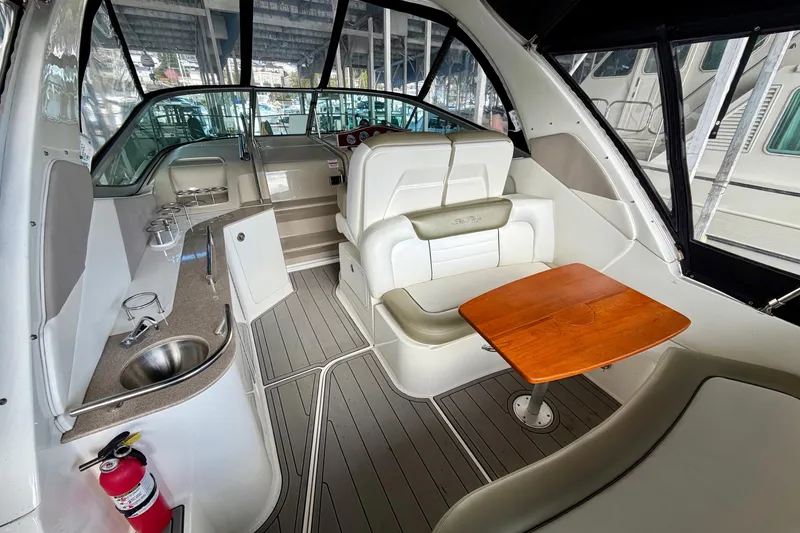 Slide: The Image of 2007 Sea Ray Sundancer 310 interior with seating, table, and kitchenette under a covered dock. - 10