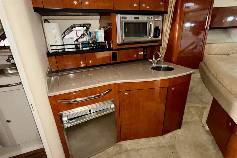 Slide: The Image of 2007 Sea Ray Sundancer 310 interior kitchen with microwave, sink, and wooden cabinetry. - 21