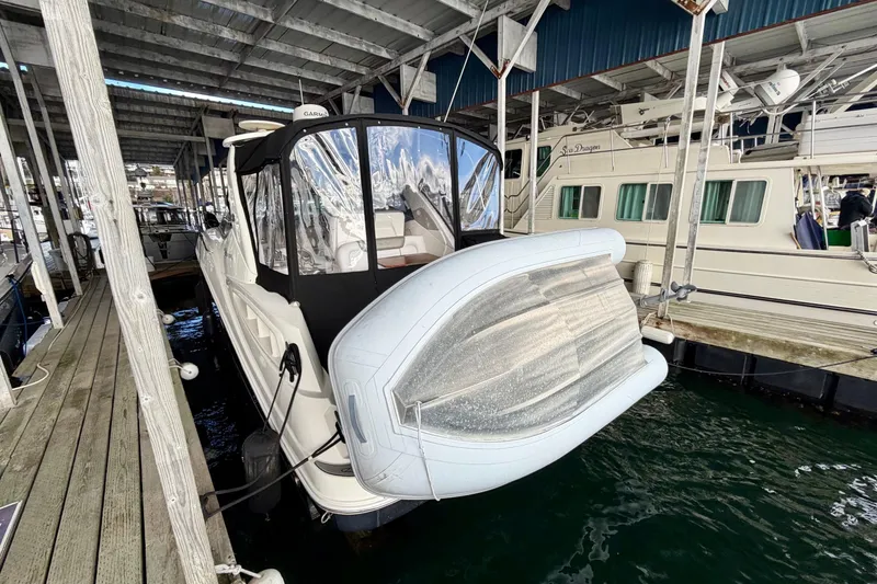Slide: The Image of 2007 Sea Ray Sundancer 310 docked under a covered marina with inflatable boat attached. - 6